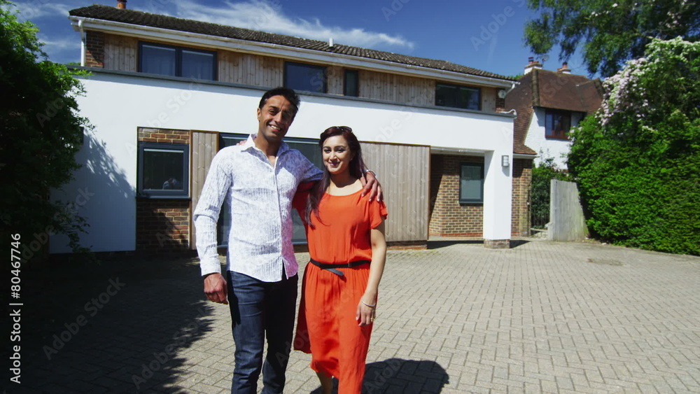 Portrait of happy asian couple standing in front of their home on a sunny day