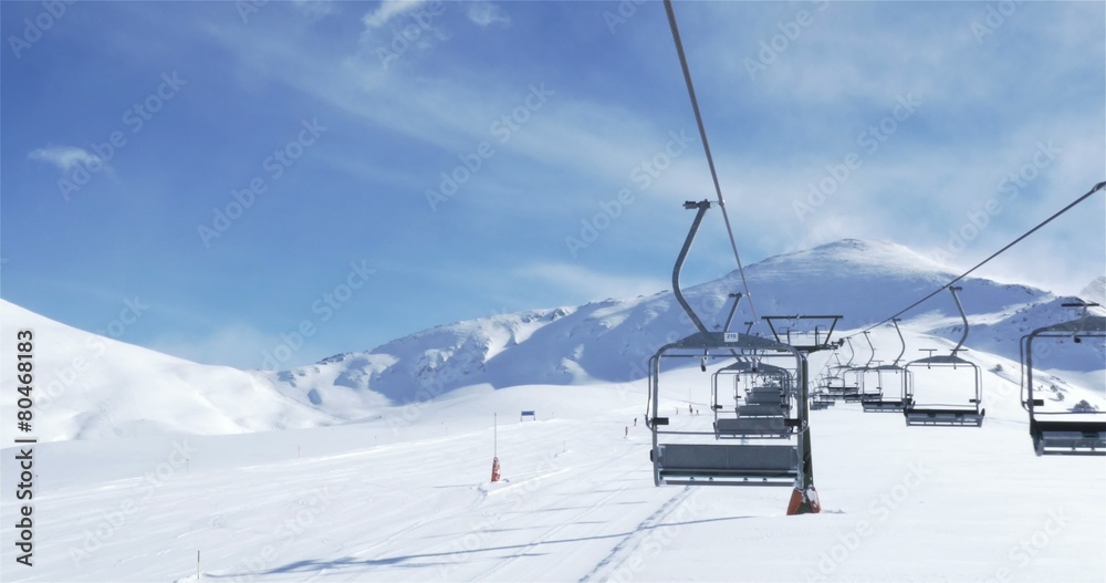 Empty Ski lift with skiers in the background Empty Ski lift with skiers in the background