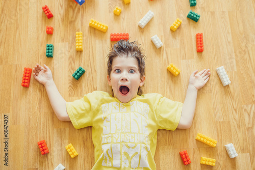 Little child is laying with colorful plastic blocks surprised photo