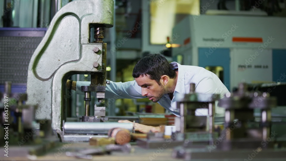 Young male machine operator working in a factory Young male machine operator working in a factory