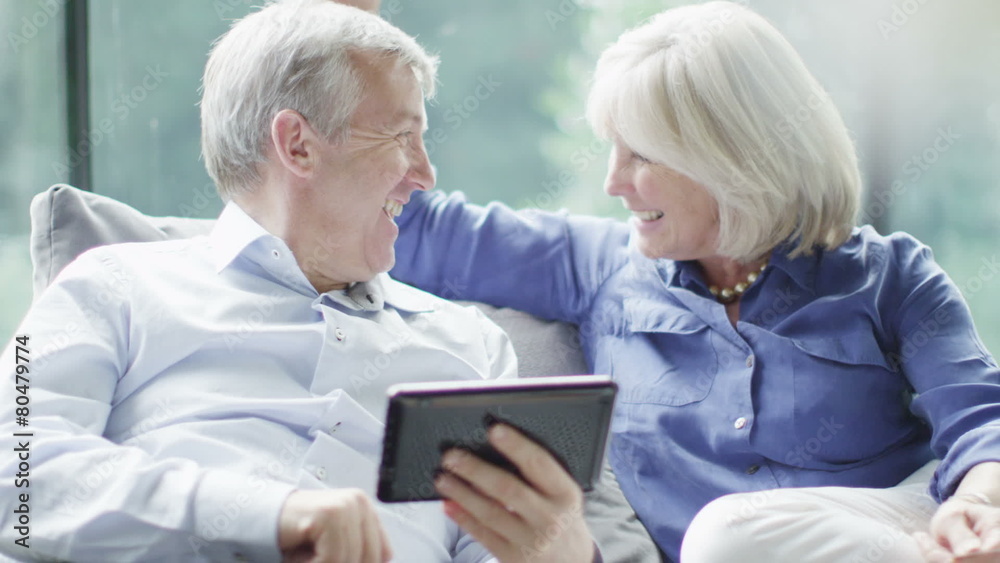 Attractive mature couple with technology shopping on the internet at home Attractive mature couple with technology shopping on the internet at home