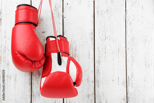 Pair of boxing gloves on color wooden background © Africa Studio