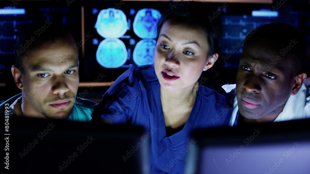 Medical team working late at a computer and discussing what they see on screen Medical team working late at a computer and discussing what they see on screen