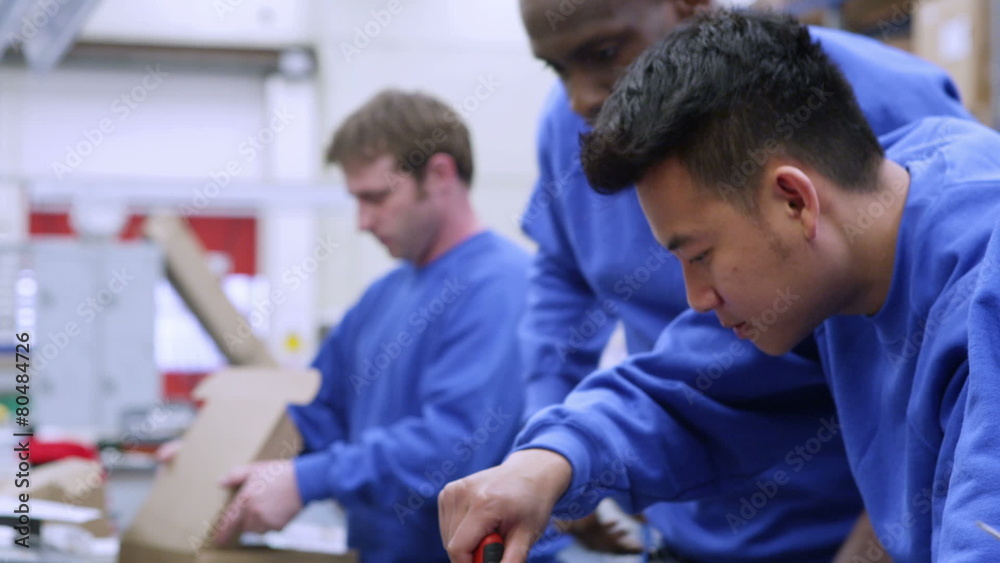 Male factory staff of mixed ethnicity working together on an assembly line