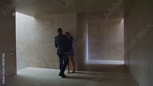 Sexy young couple walking through modern concrete building stop to share a kiss photo