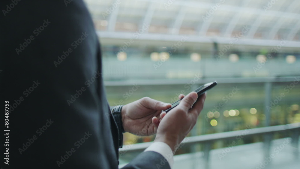 Businessman makes a phone call as he walks through a busy railway station.