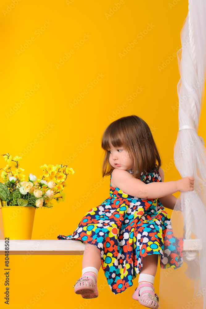 little girl sitting on swings with flowers indoors