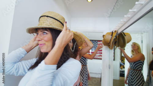 Young happy group of friends have fun trying on a selection of straw hats