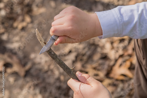 Hands of a young boy whittling a piece of wood photo