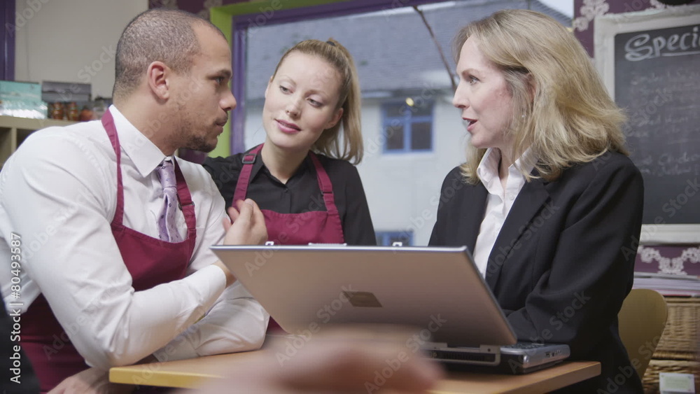 Attractive male and female coffee shop workers discuss work with their manager