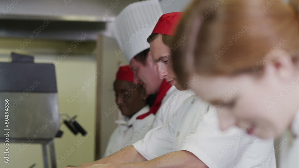 Happy team of chefs in commercial kitchen, preparing food and chatting together Happy team of chefs in commercial kitchen, preparing food and chatting together