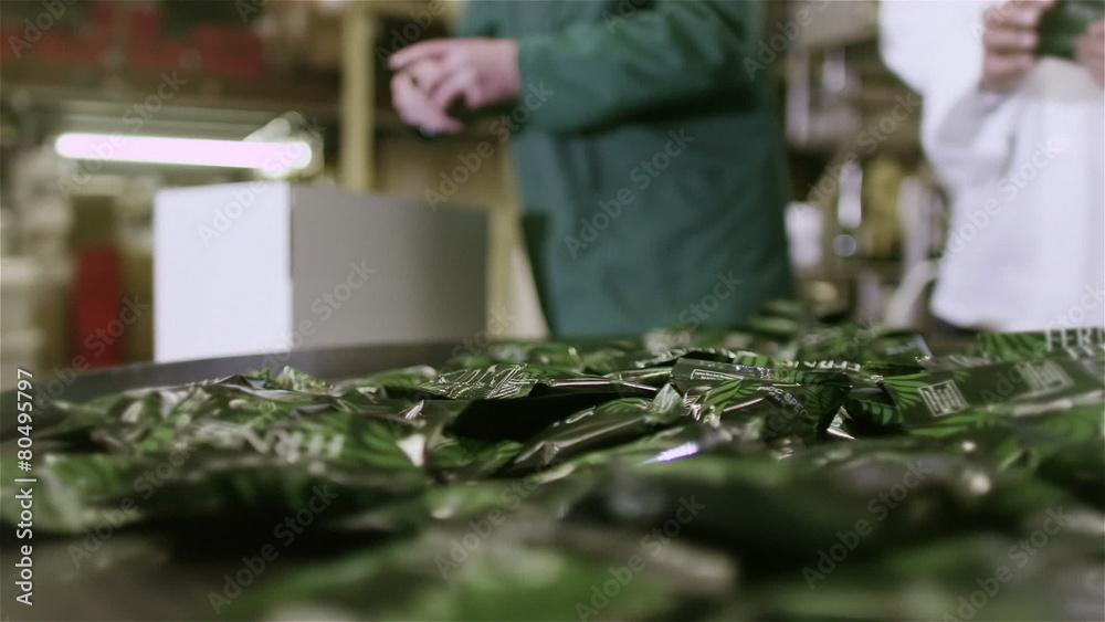 Workers in a beverage factory sorting and packing packets of fresh coffee Workers in a beverage factory sorting and packing packets of fresh coffee