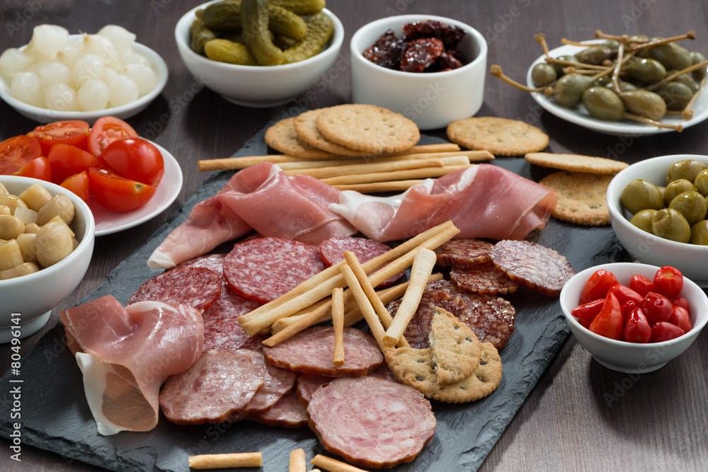 Assorted meat snacks and pickles on a blackboard