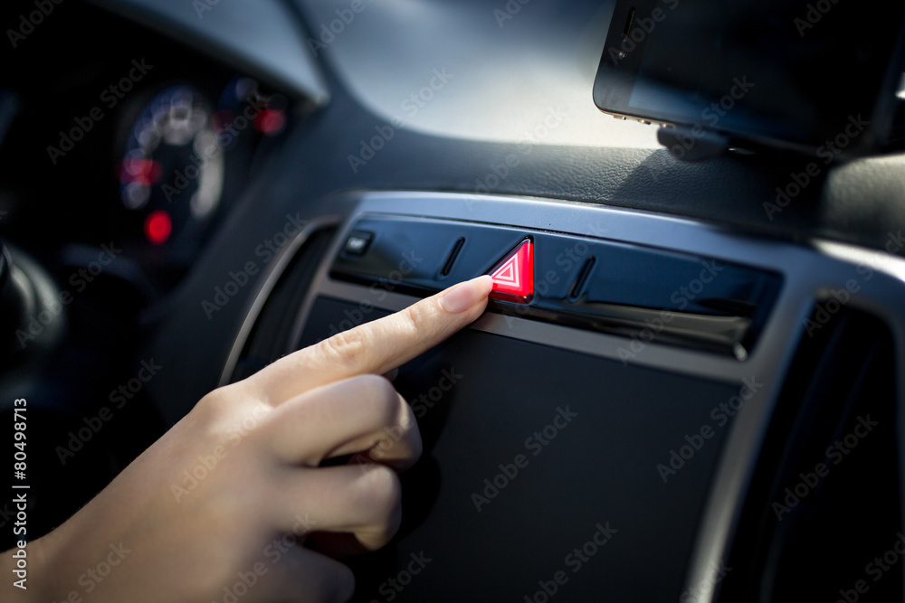 woman pressing emergency button on car dashboard
