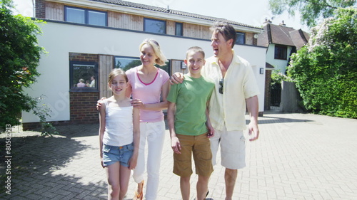 Portrait of happy caucasian family in front of their home on a sunny day
