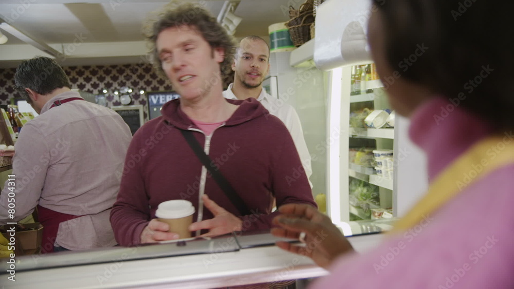 Female barista in a coffee shop serving a queue of customers Female barista in a coffee shop serving a queue of customers