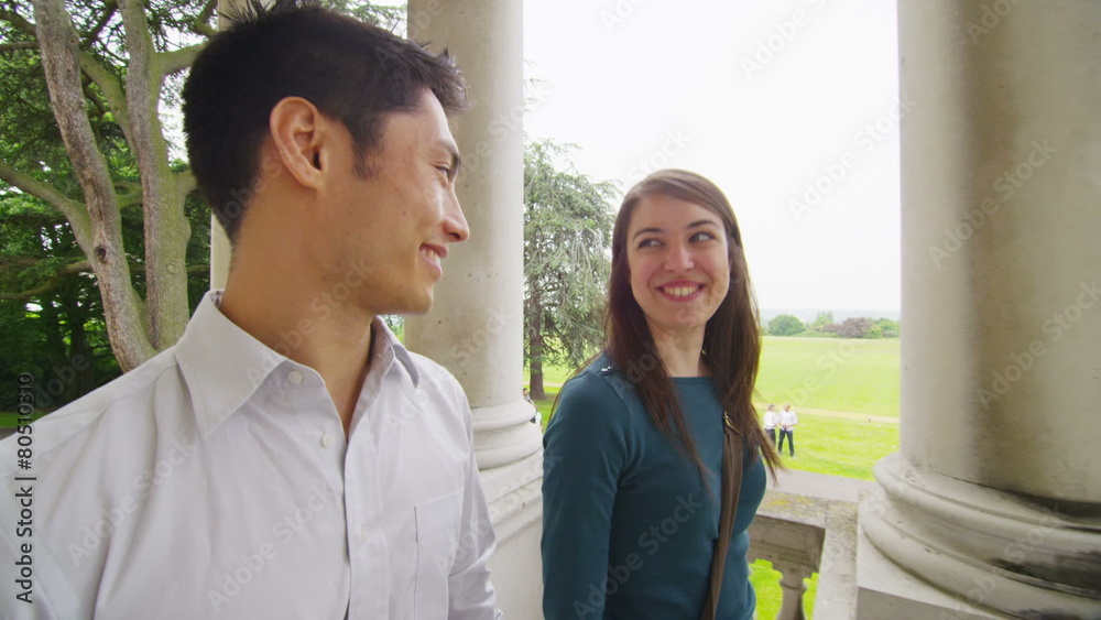 Male & female student outside college building with view of natural landscape Male & female student outside college building with view of natural landscape
