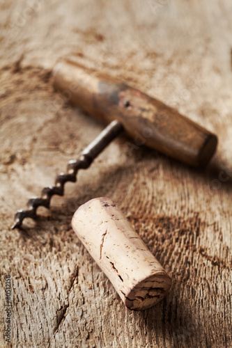 Wine cork and corkscrew on wooden table