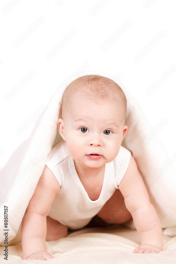 Cute baby peeking out from under the blanket,playing on the bed. Cute baby peeking out from under the blanket,playing on the bed.