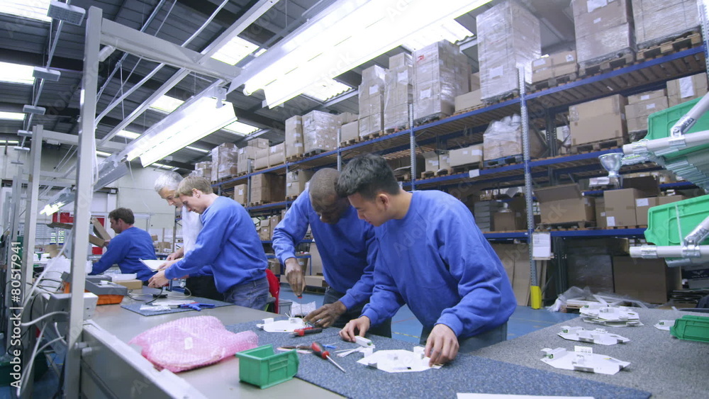Male factory staff of mixed ethnicity working together on an assembly line