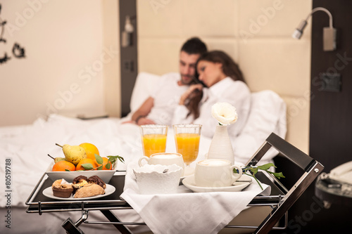 Young couple having breakfast in luxury hotel room. Focus on tra