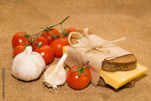 Sandwich with cheese wrapped in paper  cherry tomatoes and garli