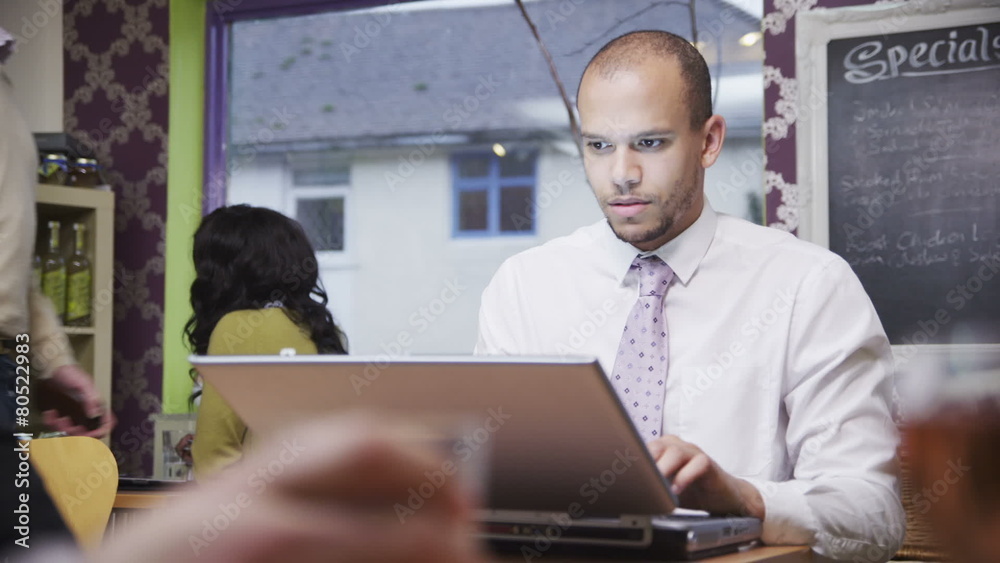 Attractive mixed race young professional male working on his laptop in a cafe Attractive mixed race young professional male working on his laptop in a cafe