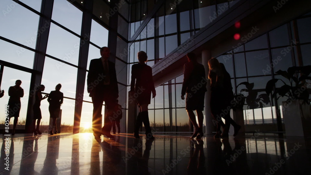 Business people walking through a modern office building at sunset