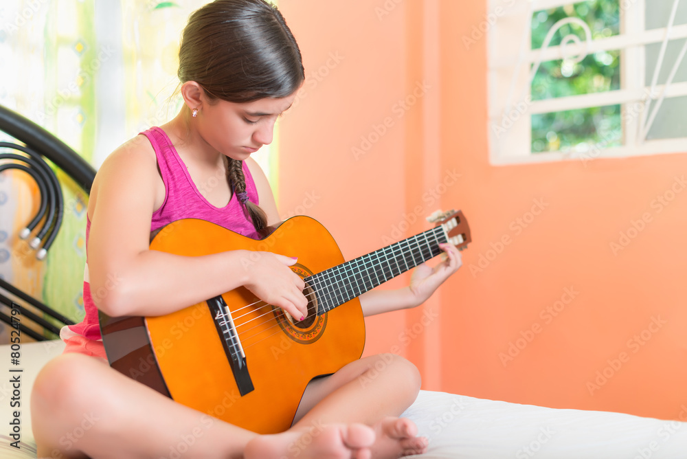 Fototapeta premium Hispanic teenage girl playing guitar at home