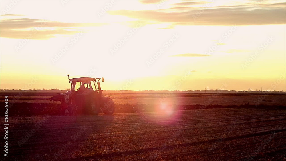 Tractor plowing field in sunset Tractor plowing field in sunset