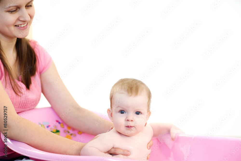 Mother washing a baby in pink bathtub Mother washing a baby in pink bathtub
