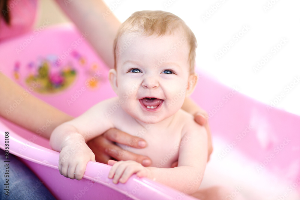 Mother washing a smiling baby in pink bathtub StockFoto Adobe Stock