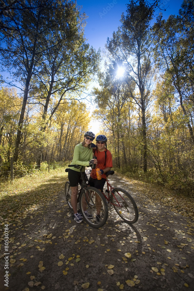 Two people with mountain bikes, taking a rest on a path having a drink. Two people with mountain bikes, taking a rest on a path having a drink.