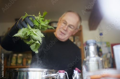 Man holding nettle above steaming saucepan