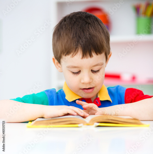 Little boy is reading a book