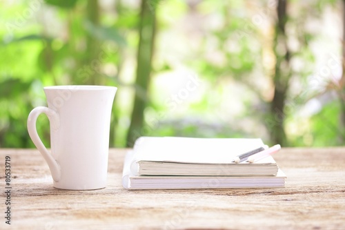 Notebook and white cup on wooden table