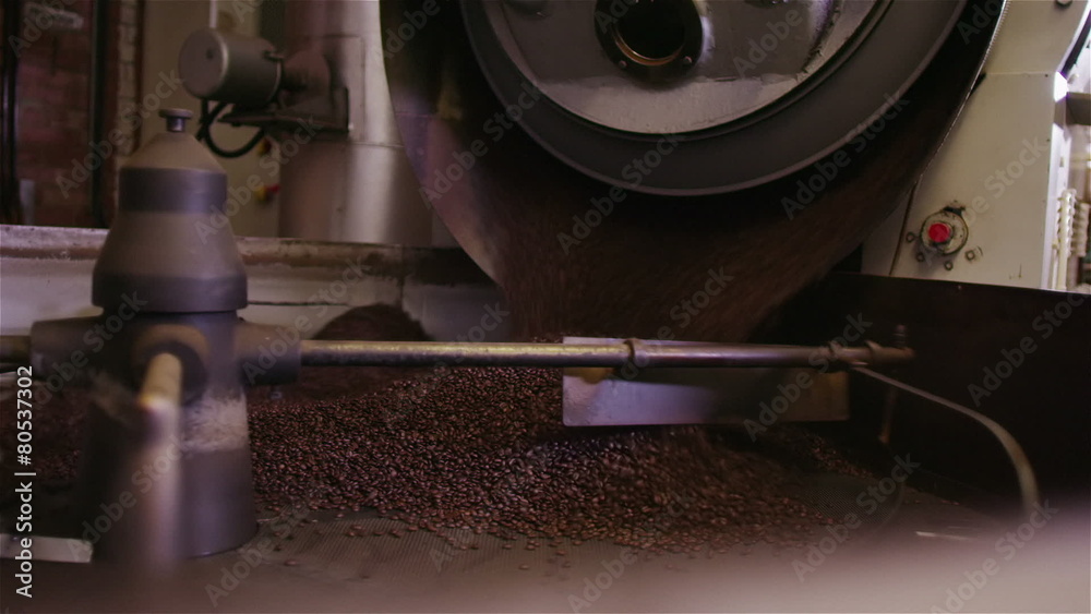 Factory machine in operation, turning and stirring roasted coffee beans Factory machine in operation, turning and stirring roasted coffee beans