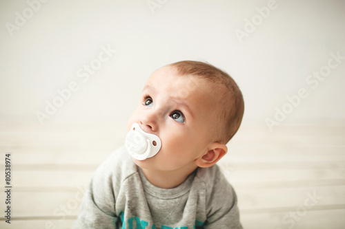 One year old cute baby boy sitting on wooden floor