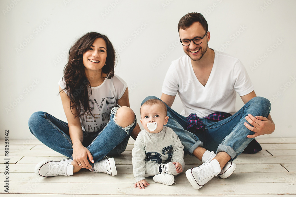 Young hipster father, mother and baby boy on wooden floor Young hipster father, mother and baby boy on wooden floor