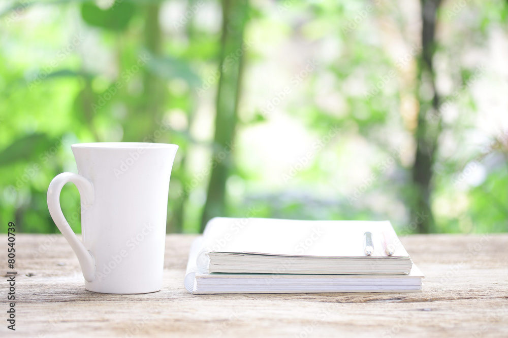 Notebook and white cup on wooden table Notebook and white cup on wooden table
