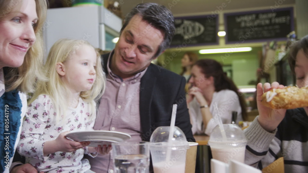 Happy affectionate family with cute children enjoying snacks and drinks in cafe Happy affectionate family with cute children enjoying snacks and drinks in cafe
