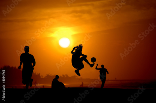 Jóvenes jugando al futbol en la playa