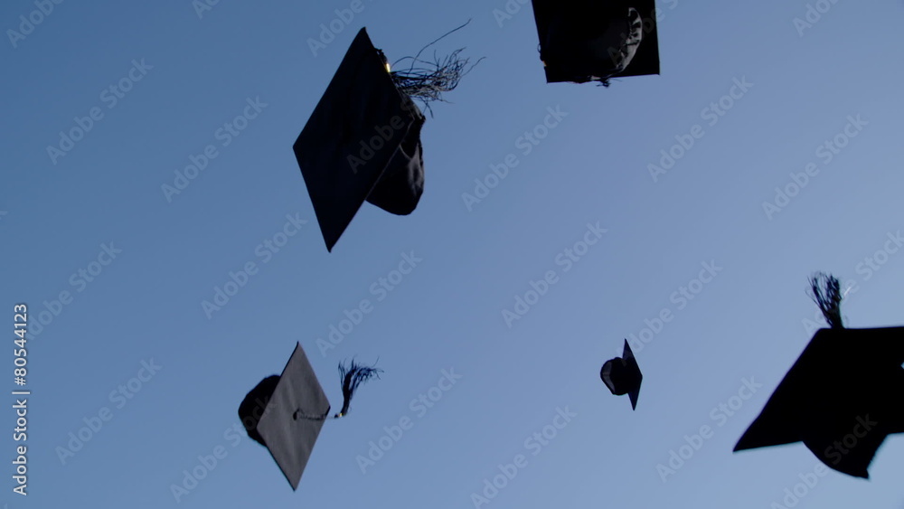 Graduation caps are tossed into the air on a bright sunny day