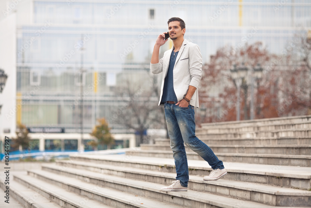 Young man walking down the stairs and talking on the phone Young man walking down the stairs and talking on the phone