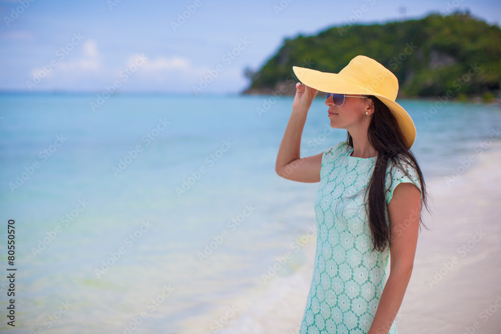 Young fashion woman in hat and dress on the beach