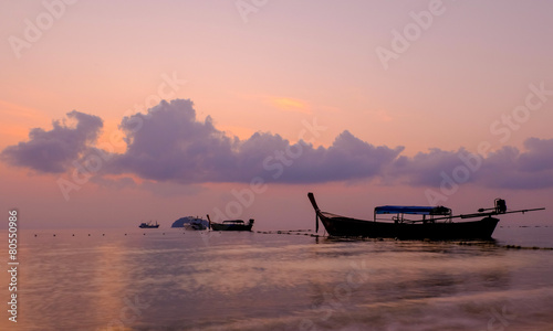 Thai boat laying on a sunrise on a calm ocean