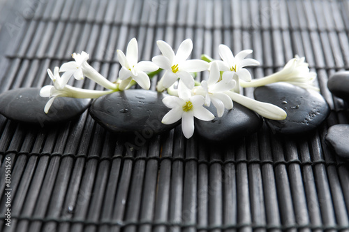 Lying down stones with white tropical flower on bamboo mat