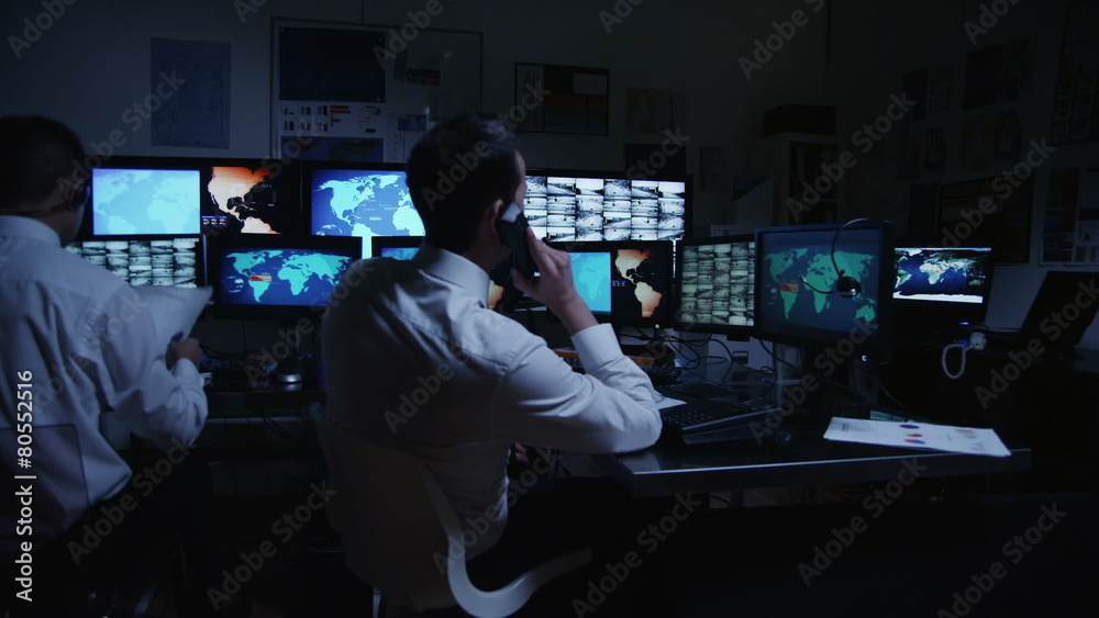 Security personnel watching the screens in a dark system control room