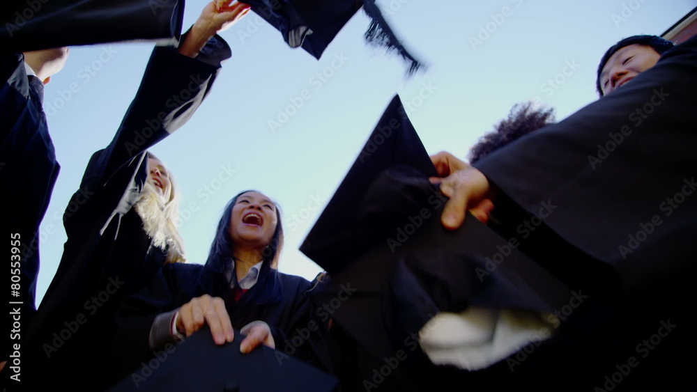 Happy multi-ethnic friends on graduation day throw their caps into the air