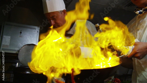 Professional chef in a restaurant kitchen cooking flambe style